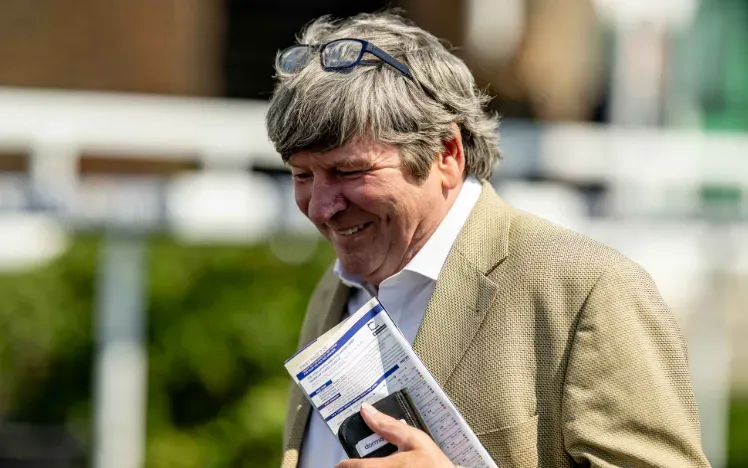 A race goer at Brighton Races holding a racecard
