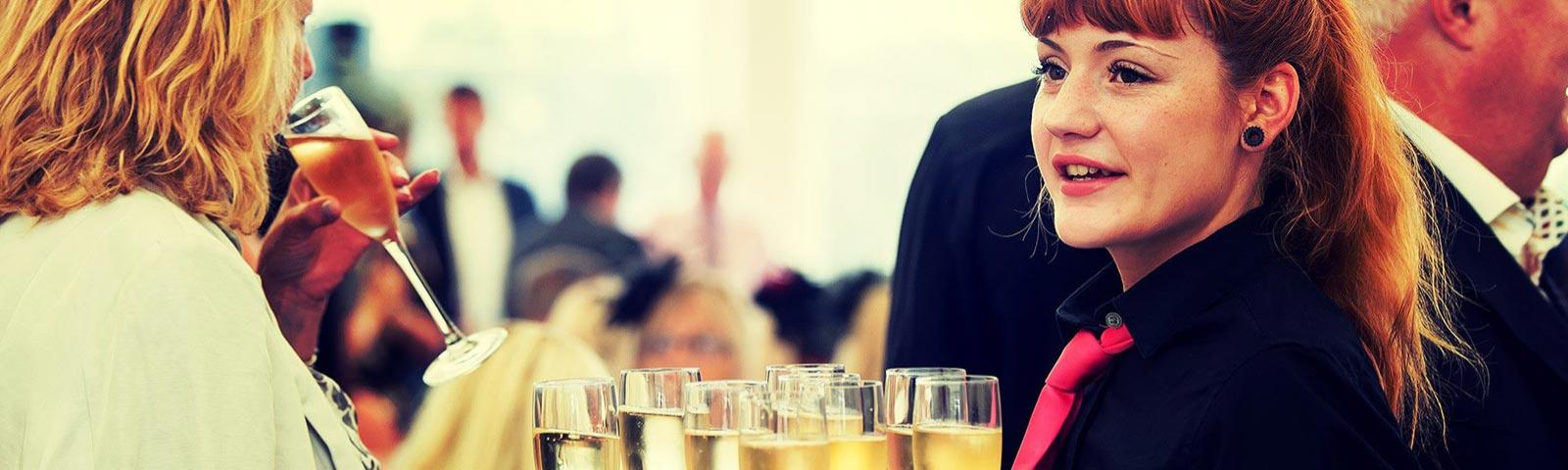 A guest receives a glass of Champagne from a member of Brighton Racecourse' waiting staff.