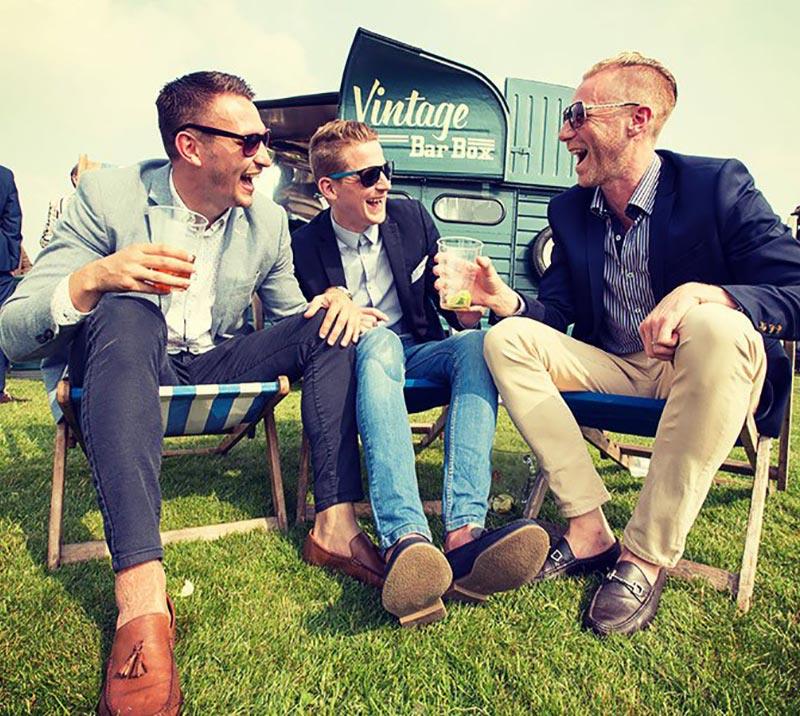 Three gentlemen sitting in beach chairs in front of a vintage bar.