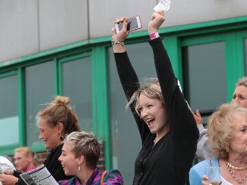 A race goer celebrating her win at Brighton Races with her arms in the air