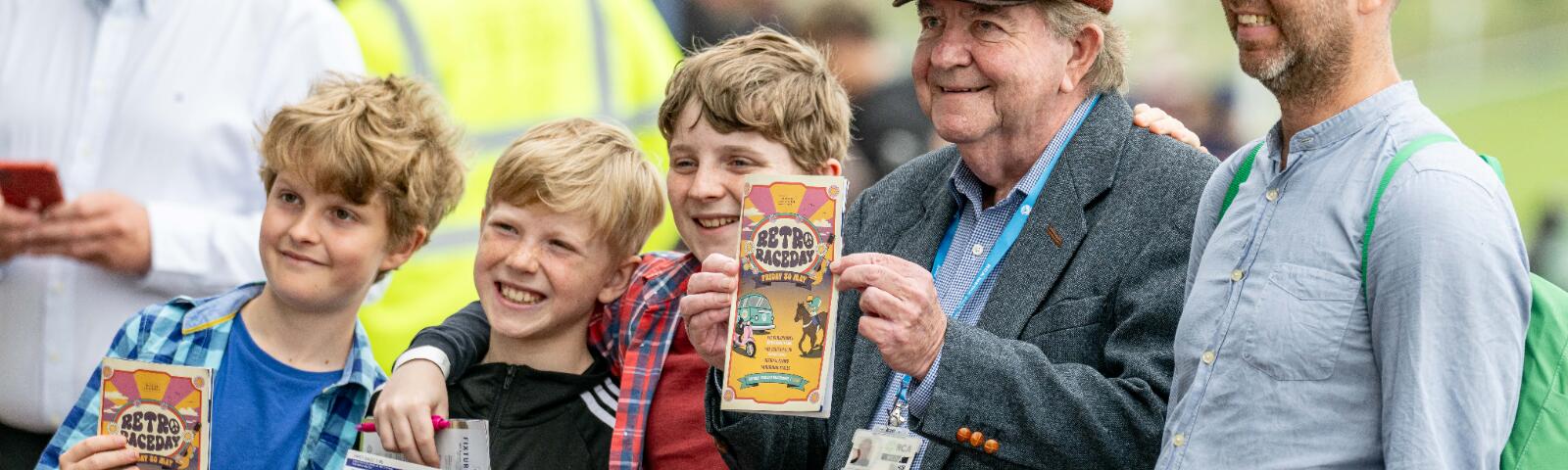 A group of racegoers at Brighton old and young pose with their horse race cards.