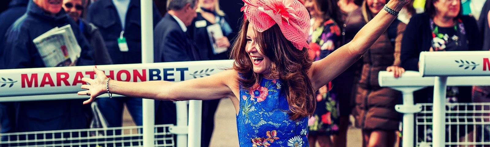 A dressed up lady attending races at Brighton Racecourse.